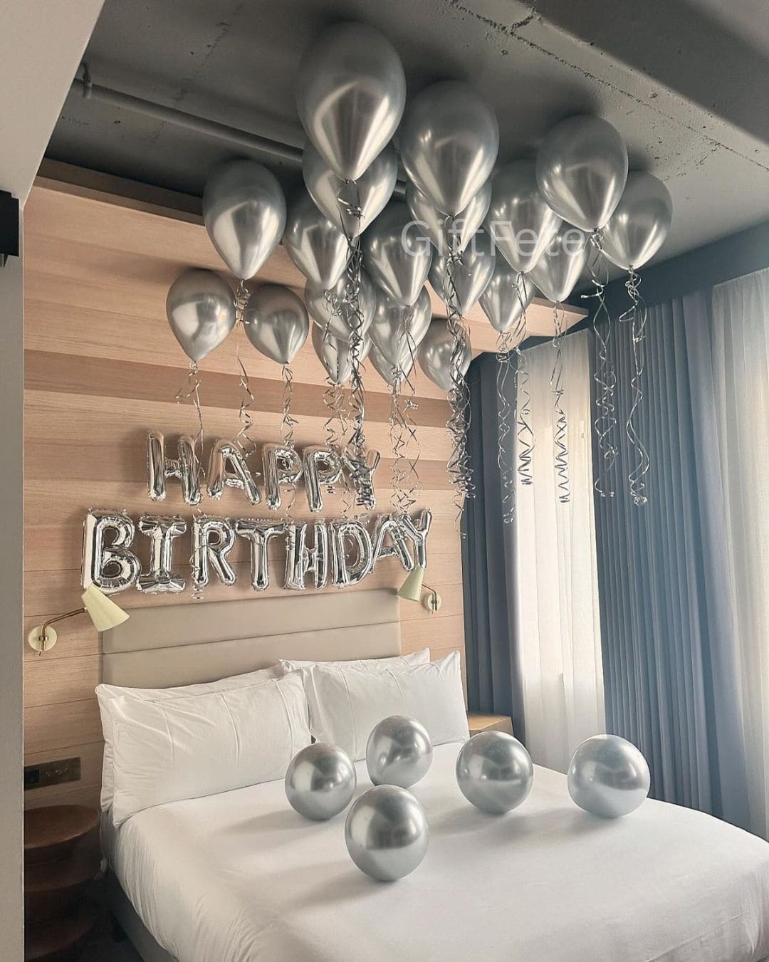 Silver balloons and 'Happy Birthday' banner in a bedroom setting