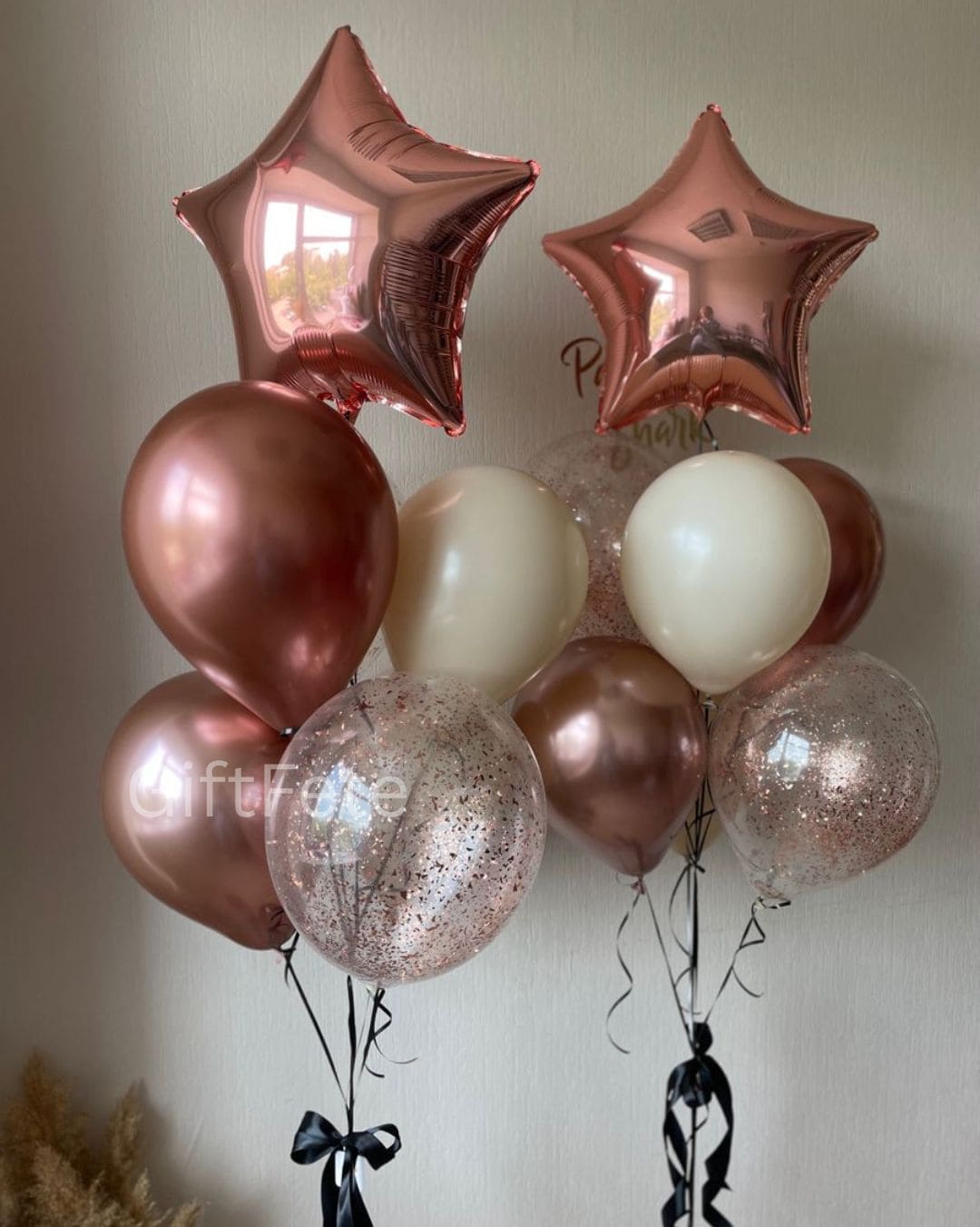 Rose gold and white balloons with star-shaped balloons against a plain background