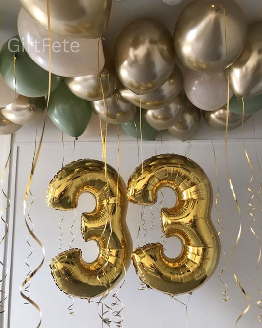 Gold number 33 balloons with green and silver balloons on a white background