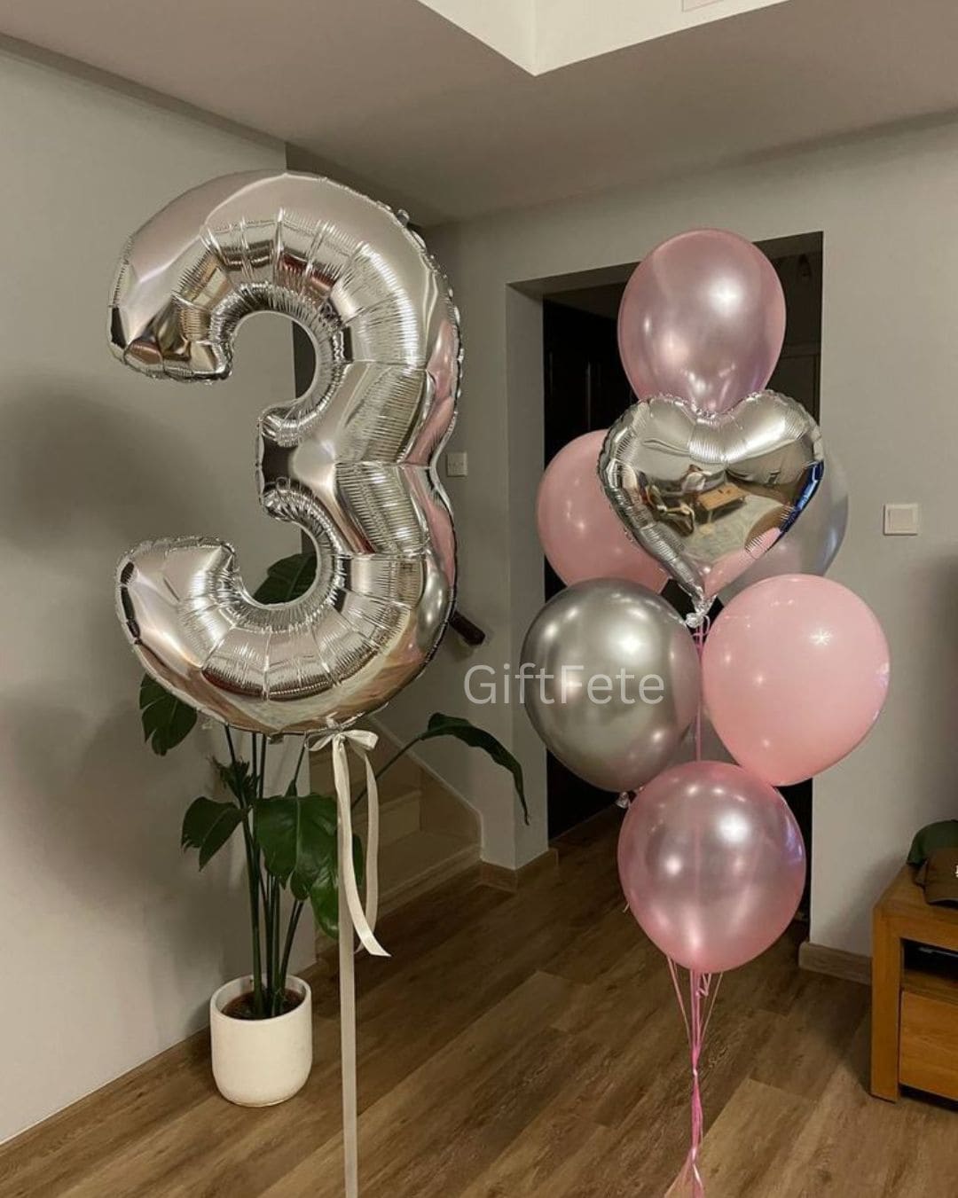 Silver number 3 balloon and pink balloons with a heart shape in a room.